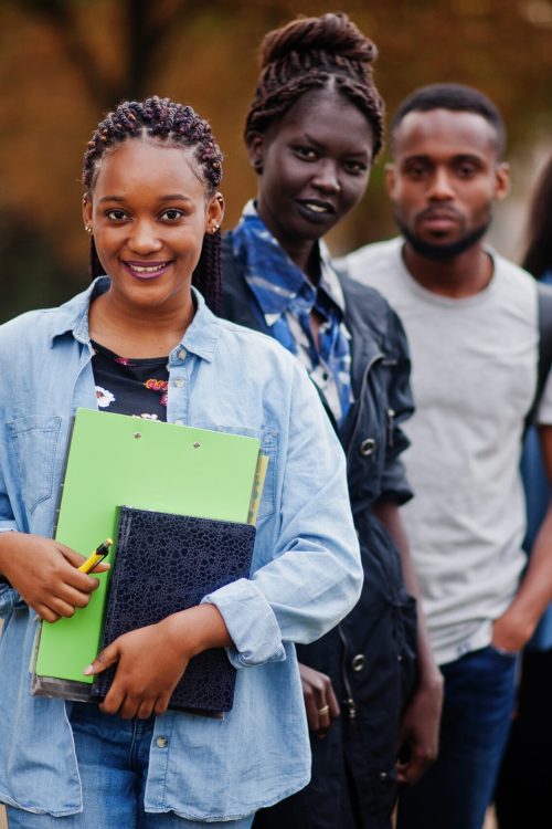 Row of group five african college students spending time together on campus at university yard. Black afro friends studying. Education theme.